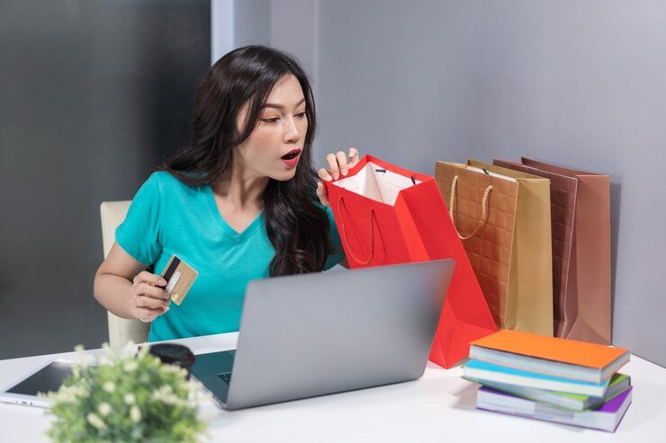 surprised woman holding credit card looking her shopping bag table